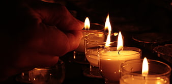 Hand Lighting Candles in Dark Church Atmosphere
