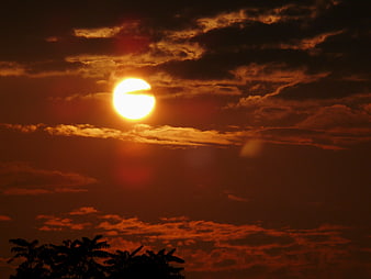 Dramatic orange sunset with sun silhouette and clouds