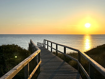 Wooden Boardwalk Leading to Calm Ocean at Golden Sunset