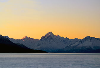 Snowy Mountain Peaks at Sunset Over Calm Lake