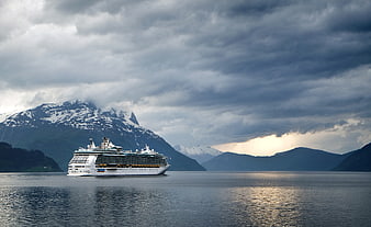 Cruise Ship Sailing Past Snowy Mountains Under Dramatic Clouds