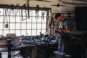 Blacksmith Working In Traditional Workshop With Tools