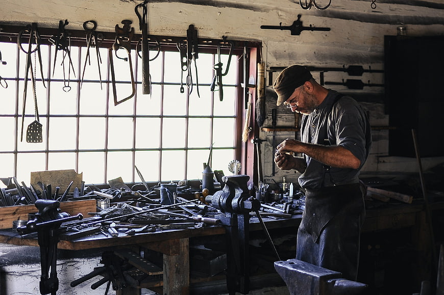 Blacksmith Working In Traditional Workshop With Tools