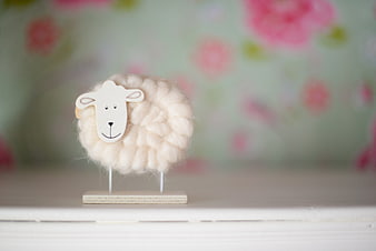 Cute felted wool sheep toy on wooden stand