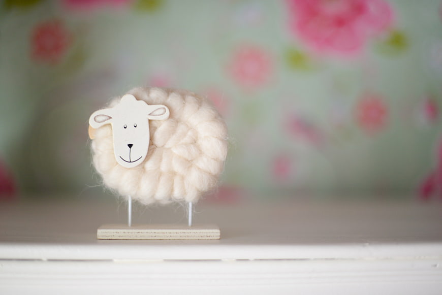 Cute felted wool sheep toy on wooden stand