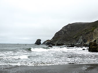 Dramatic Rocky Coastline with Crashing Waves and Overcast Sky