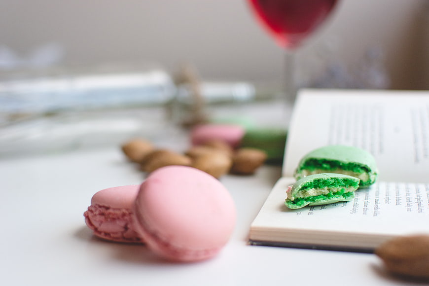 Pink and Green Macarons on Open Book with Wine