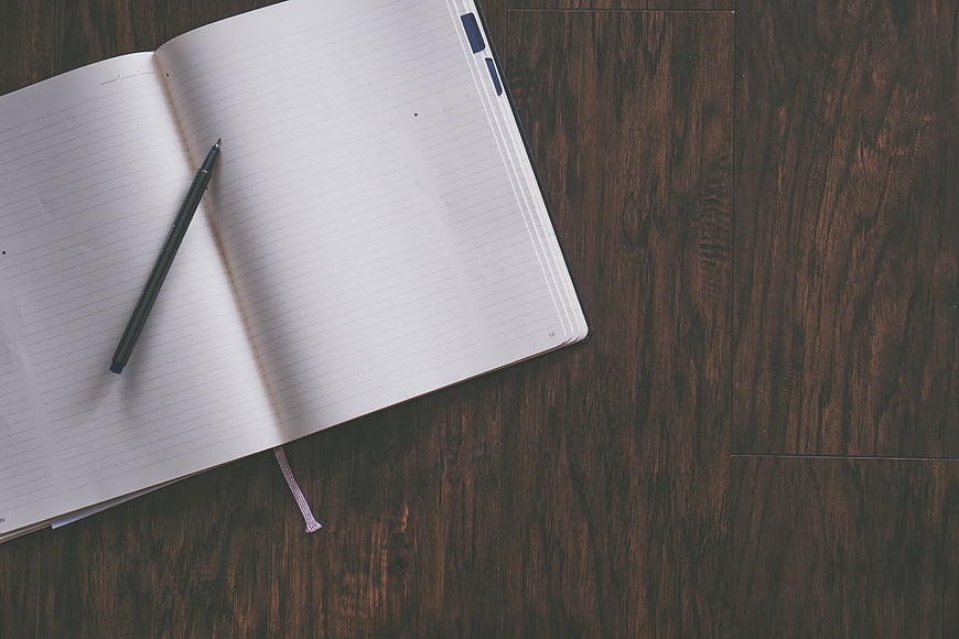 Open Notebook and Pen on Dark Wood Surface