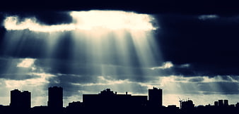 Dramatic Sun Rays Breaking Through Clouds Over City Skyline