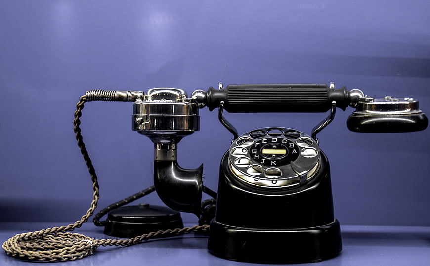 Vintage black rotary telephone on blue background