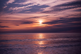 Vibrant purple and orange sunset over ocean with clouds