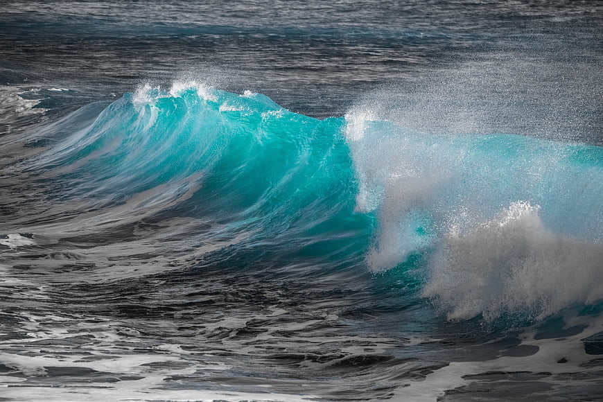 Powerful turquoise ocean wave crashing with white sea spray