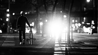 Man Walking with Bicycle on City Street at Night