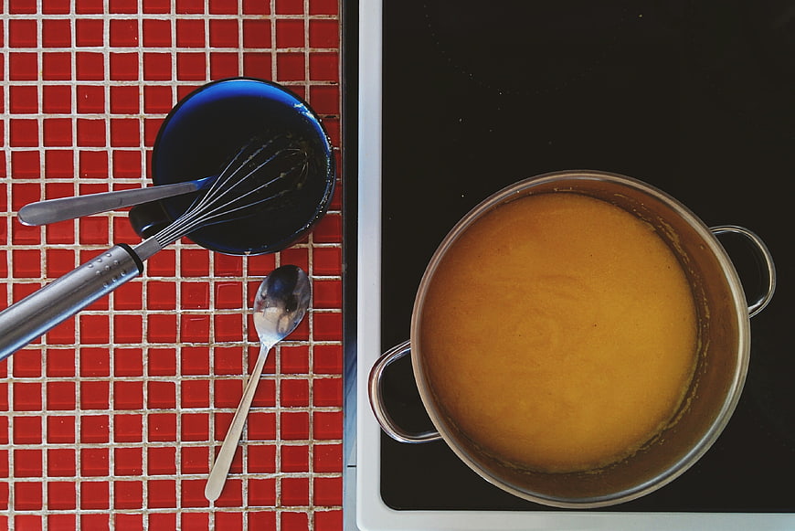 Top view of cooking polenta in pot with kitchen utensils
