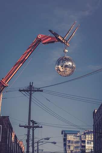 Crane lifting disco ball against blue sky