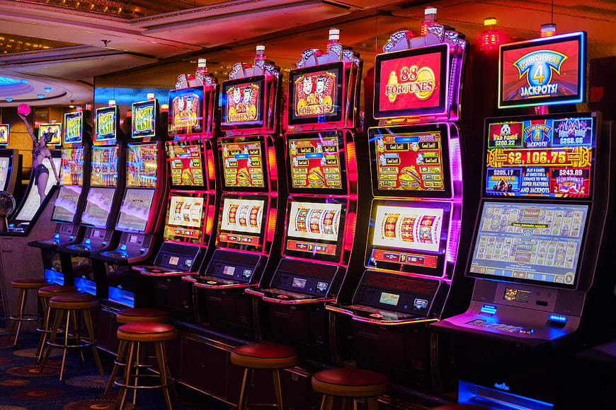 Row of illuminated slot machines in a modern casino gaming floor