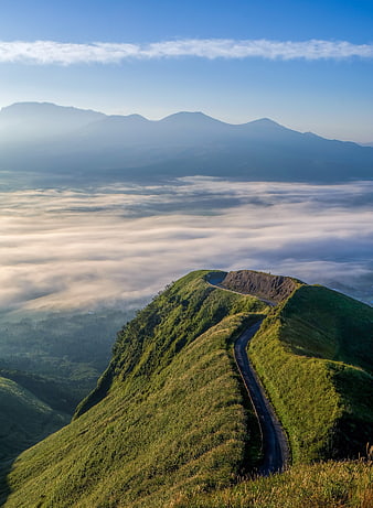 Winding mountain road above sea of clouds at sunrise