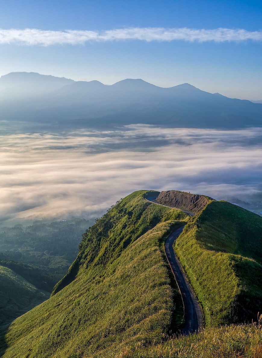 Winding mountain road above sea of clouds at sunrise