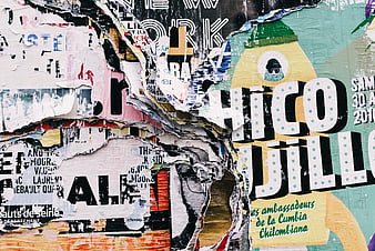 Textured urban wall with layered torn posters and street art