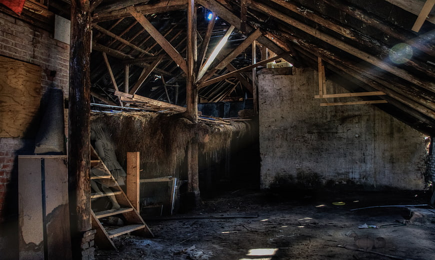 Abandoned rustic barn interior with wooden beams and hay