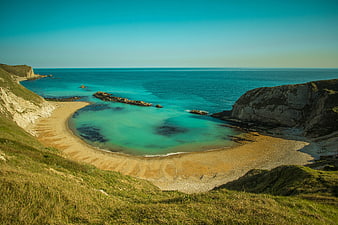 Secluded sandy beach cove with turquoise water and cliffs