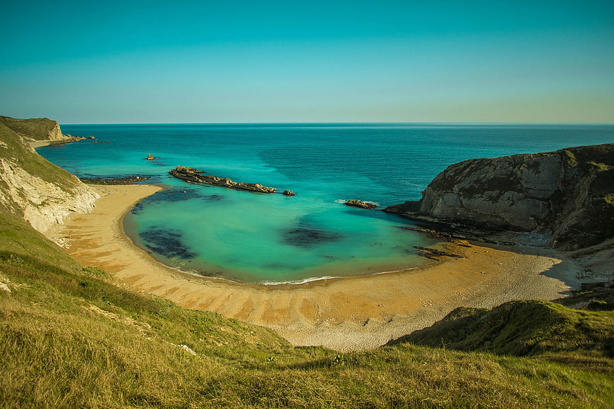 Secluded sandy beach cove with turquoise water and cliffs