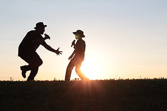 Silhouette of father and son singing with microphones at sunset