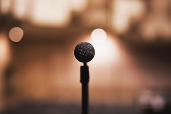 Close-up of a microphone on a stand with warm bokeh background
