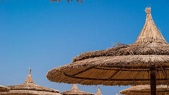 Thatched Beach Umbrellas Against Clear Blue Sky