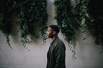 Profile of Young Black Man Standing Against Ivy Wall