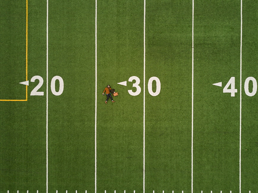 Aerial view of two people walking on a football field