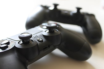 Close-up of two black video game controllers on white surface