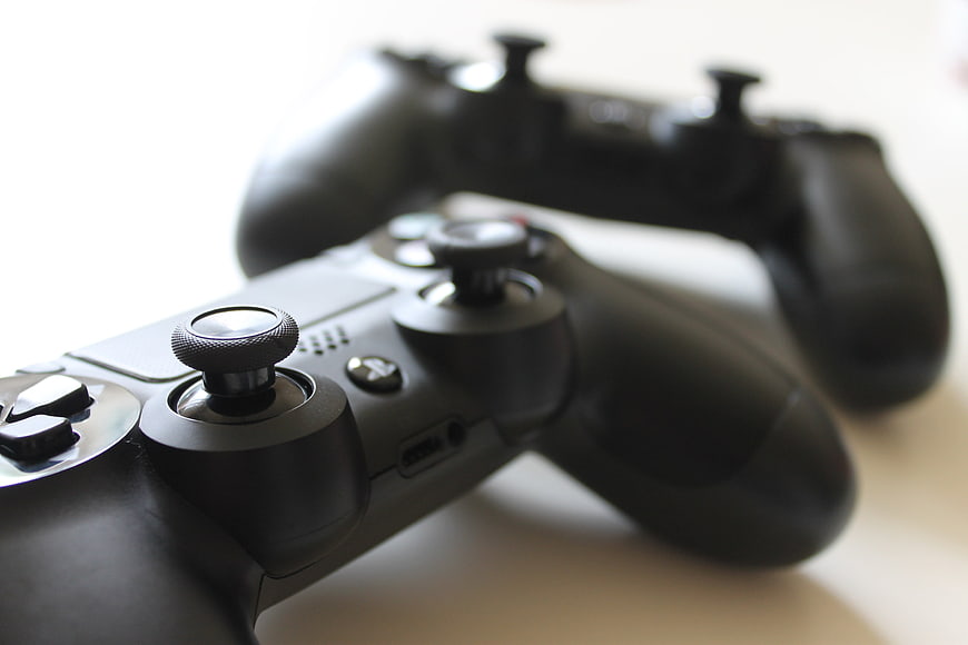 Close-up of two black video game controllers on white surface