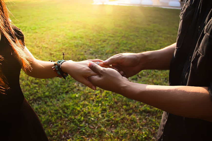 Couple holding hands in a park at sunset