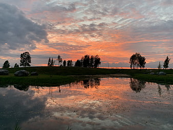 Vibrant Sunset Reflection in a Serene Lake with Silhouetted Trees