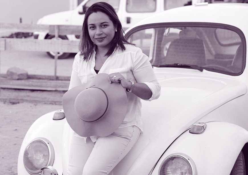 Woman with hat leaning on vintage white car