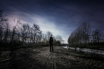 Man standing in a field under a starry night sky