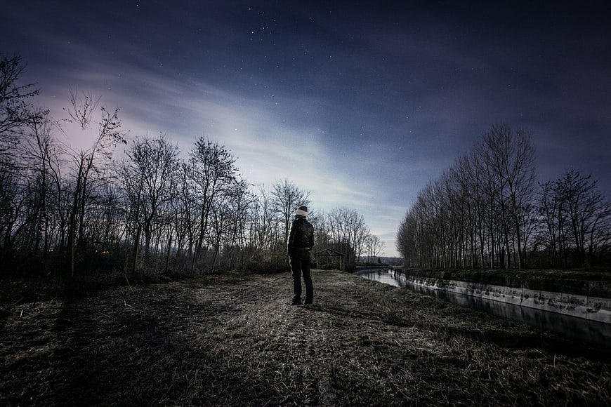 Man standing in a field under a starry night sky