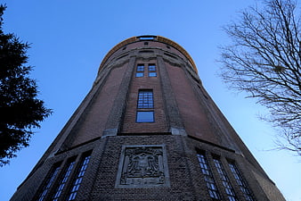 Low angle view of historic brick water tower against blue sky