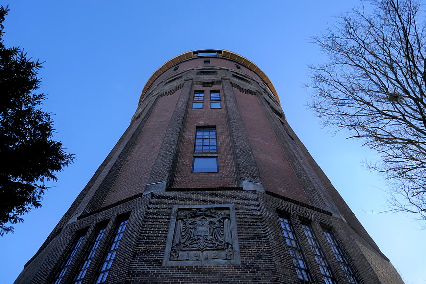 Low angle view of historic brick water tower against blue sky