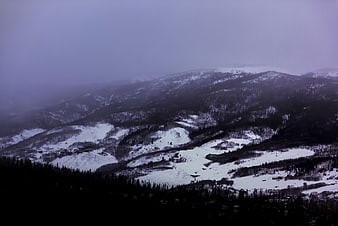 Misty Snow-Covered Mountain Landscape with Dark Forest