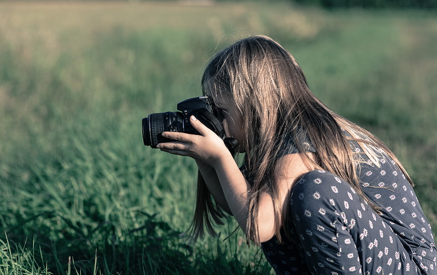 Young Girl Taking Photo with DSLR Camera in Field
