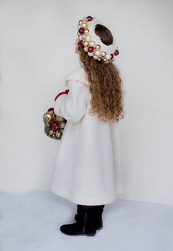 Little girl in white winter coat and Christmas ornament headband