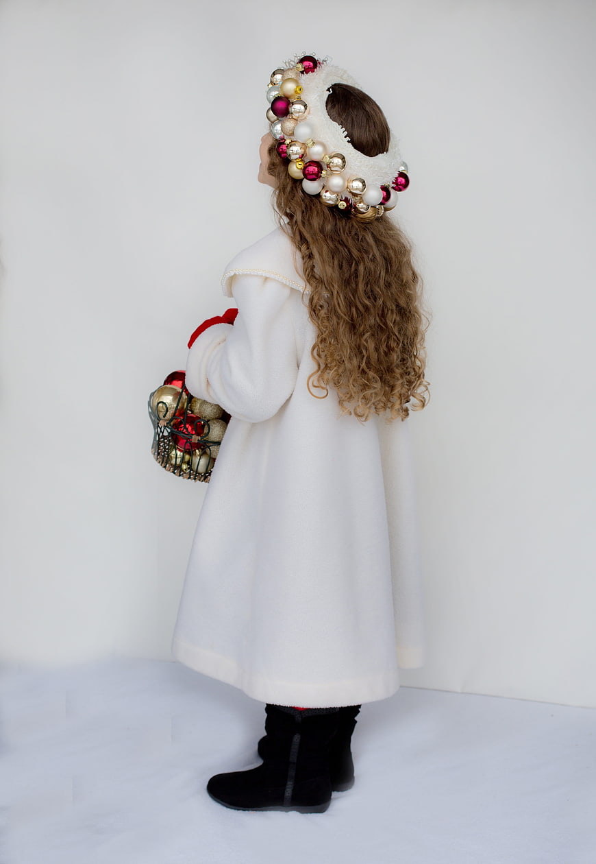 Little girl in white winter coat and Christmas ornament headband