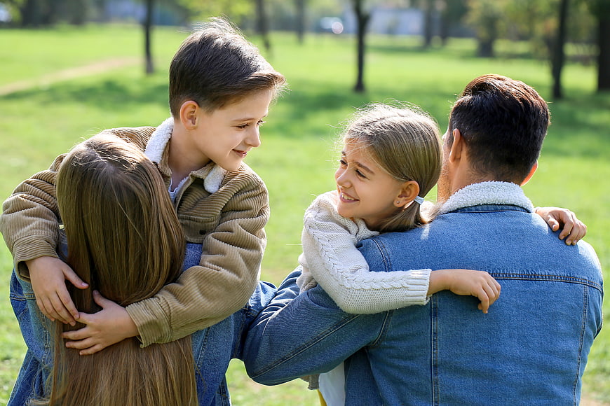 Happy family hugging together in a sunny park