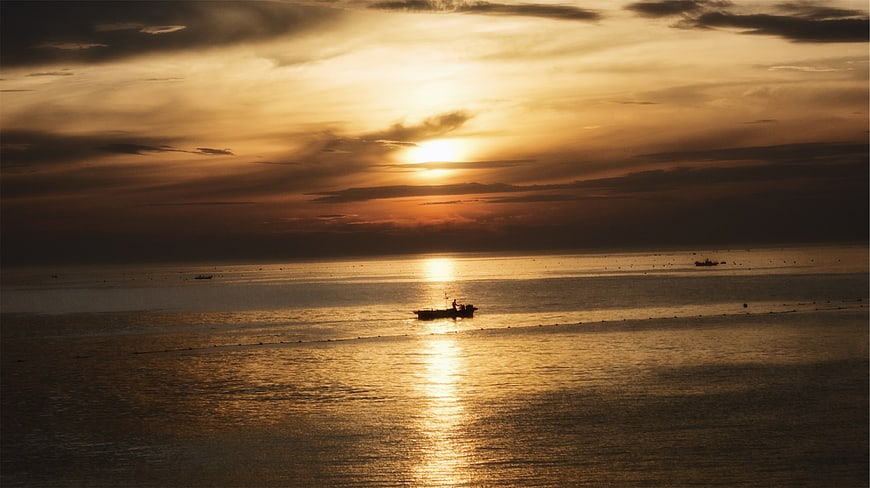 Silhouette of Fishing Boat on Golden Sunset Ocean