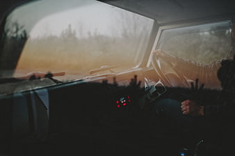 Person driving car at sunset with warm light