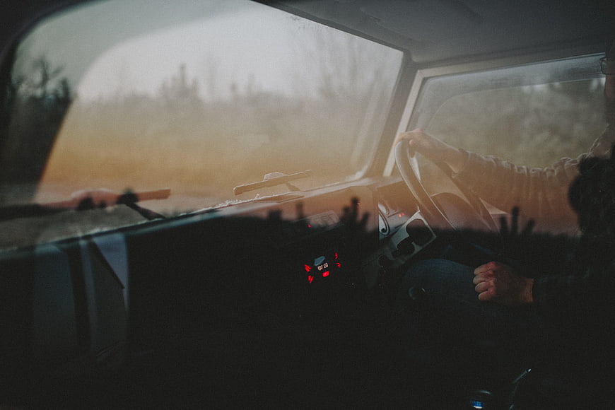 Person driving car at sunset with warm light