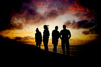Silhouette of Four Friends Watching Dramatic Sunset at Beach