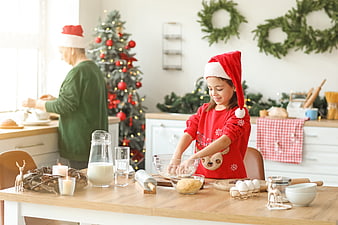 Granddaughter baking Christmas cookies with grandmother in festive kitchen